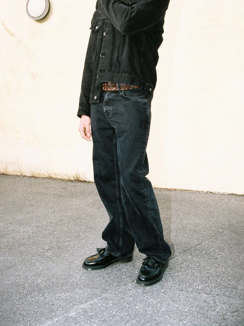 Model trägt Tuff Tony von Nudie Jeans in Black Vintage – Jeans mit entspannter Passform und mittelhohem Bund